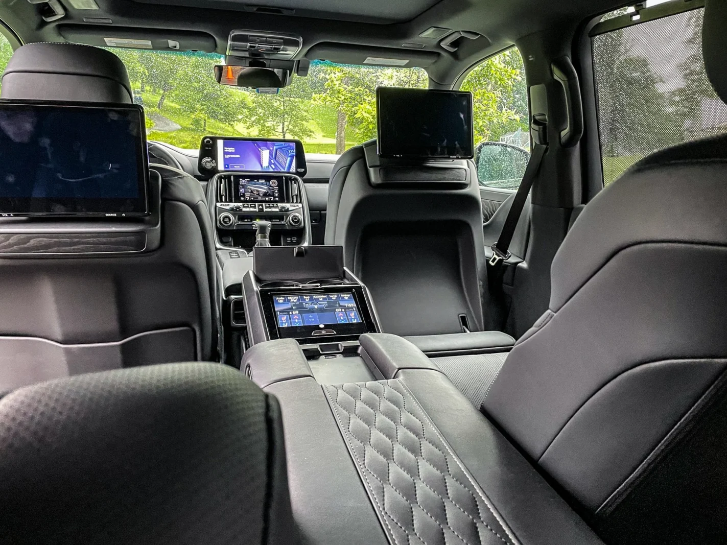 Luxury SUV interior with black quilted leather seats, entertainment screens and premium center console