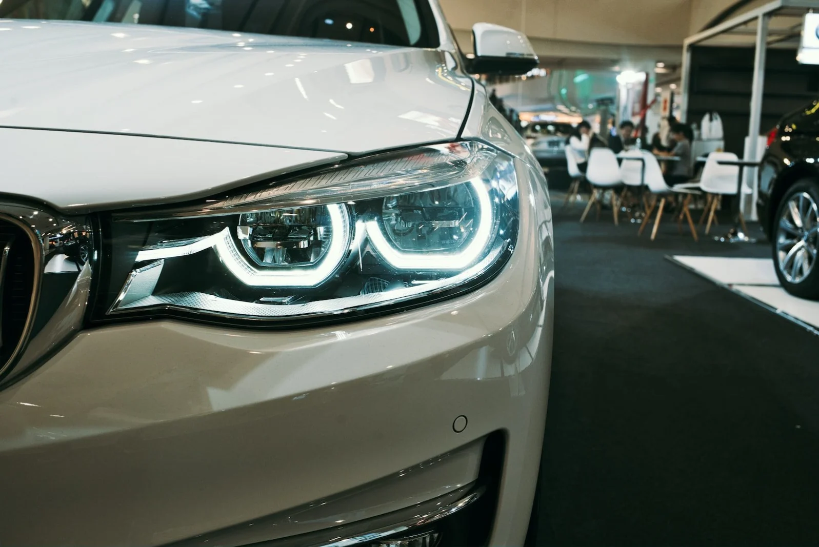 Close-up of white BMW luxury sedan LED headlights and front grille in showroom