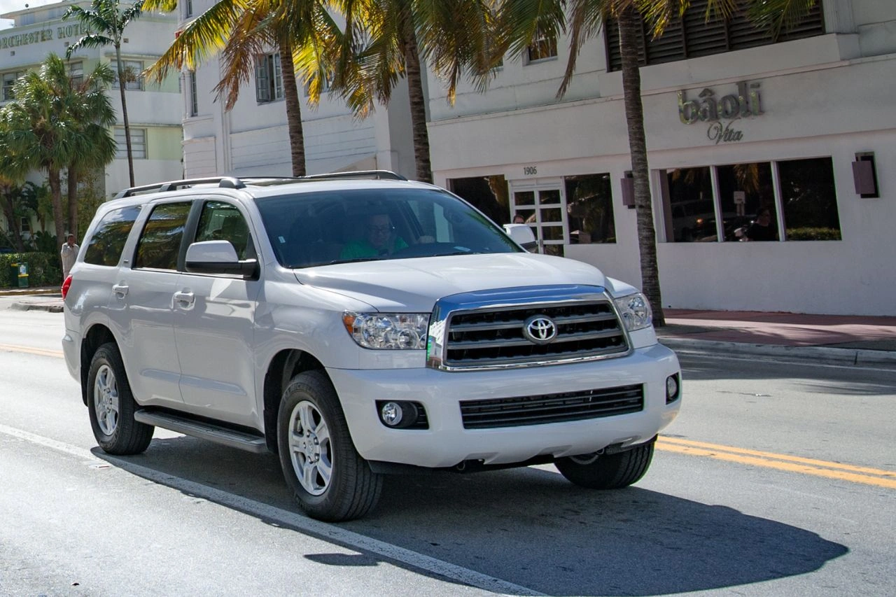 White Toyota Land Cruiser SUV parked on street with palm trees in background